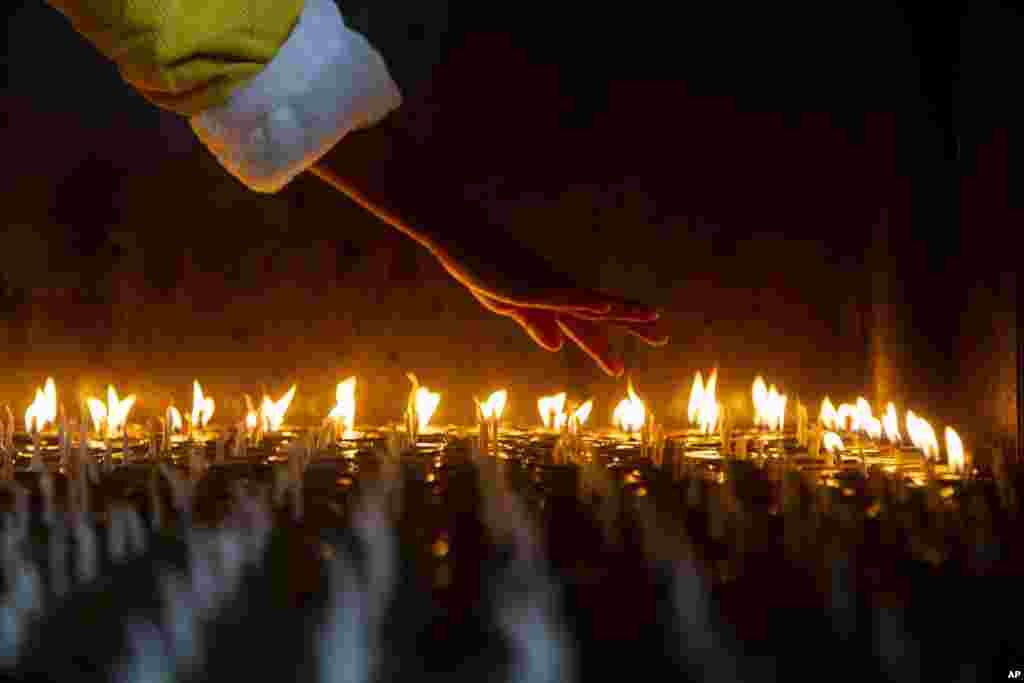 A devotee counts butter lamps before she lights them at the Boudhanath Stupa in Kathmandu, Nepal.