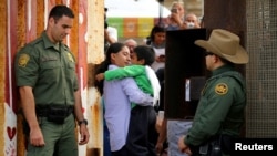 Agentes fronterizos de EE.UU. resguardan una puerta abierta en la frontera con México para permitir que Luis Eduardo Hernandez-Bautista abrace aTy'Jahnae Williams como parte del Día Universal de los Niños en el Border Field State Park, California. Nov. 19, 2016.
