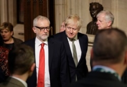 FILE - Britain's Prime Minister Boris Johnson, center right, and opposition Labour Party Leader Jeremy Corbyn walk through the Commons Members Lobby, during the state opening of Parliament, in London, Dec. 19, 2019.